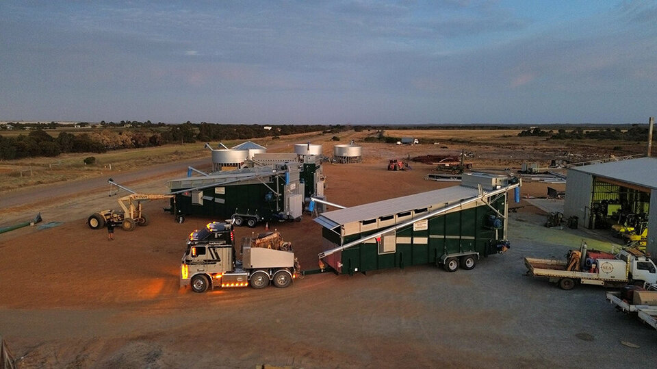 A busy yard at night. An Alvan Blanch dryer is being positioned outside a shed