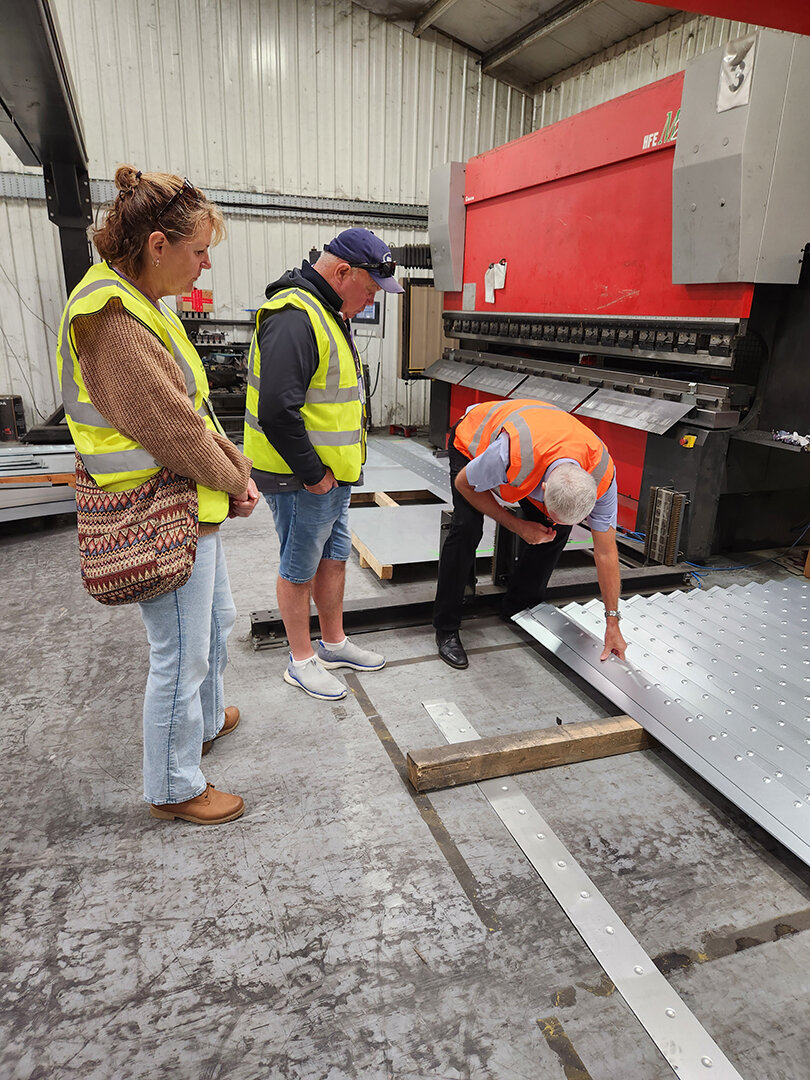 Three people wear hi-viz vests as they learn about the building process of an Alvan Blanch Dryer